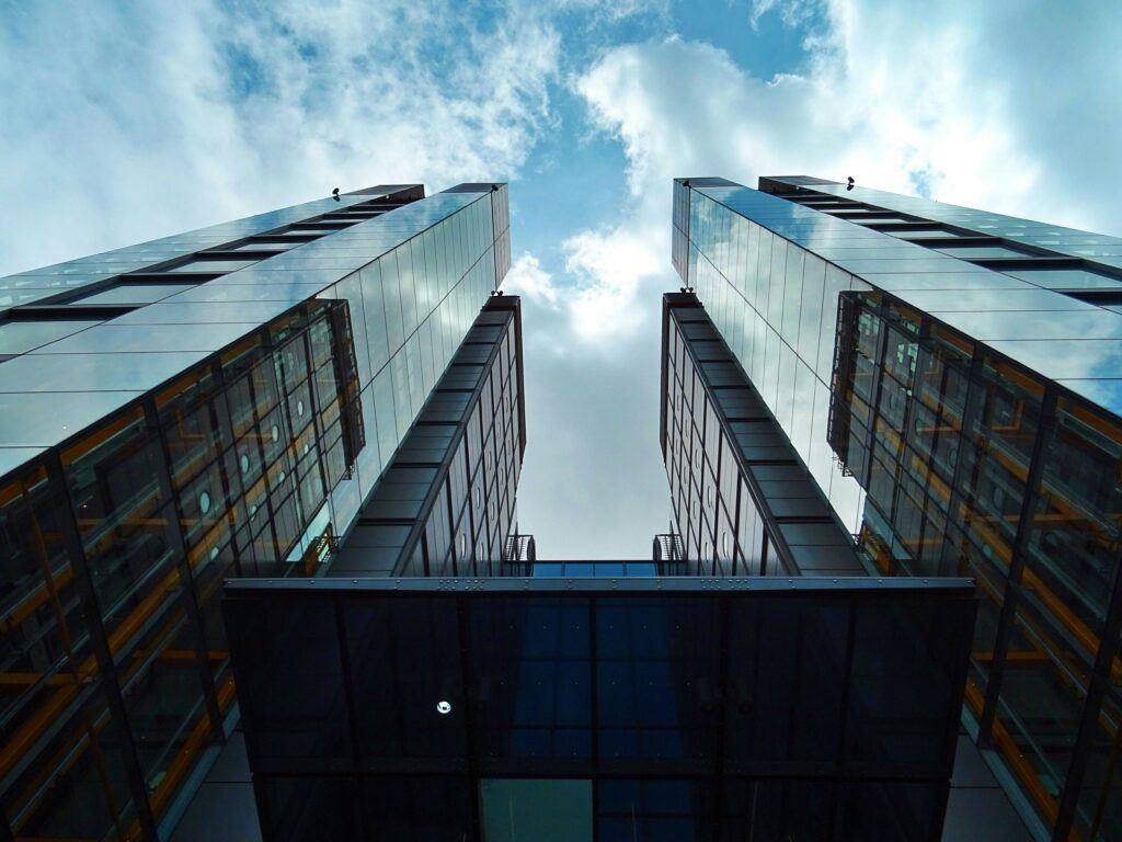 Low-angle view of sleek, modern skyscrapers with glass facades under a blue sky.